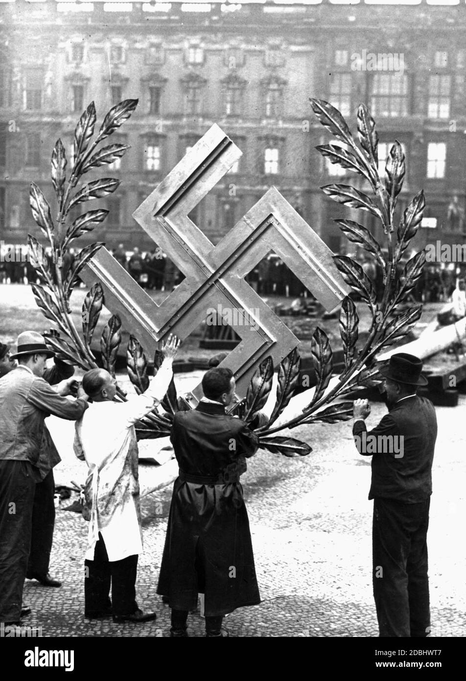 Reichswehr-Pioniere montieren ein Hakenkreuz auf einen Maibaum. Stockfoto
