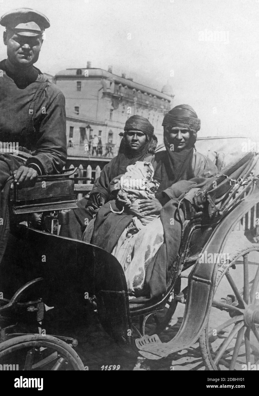 Eine Kosakenfrau mit ihrem Kind in einer Kutsche, die durch eine von Kosaken besetzte Stadt in Südrussland fährt. Stockfoto