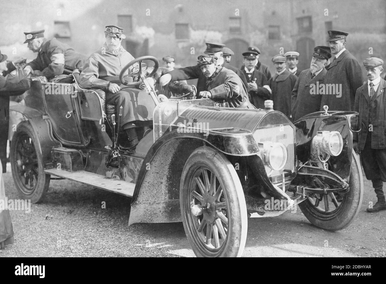 Prinz Heinrich von Preußen (Mitte links) sitzt am Steuer seines Autos (ein 40-PS-Benz mit der Nummer 75) während der Hercomer-Fahrt von 1906, die zwischen dem 6. Und 12. Juni stattfand. Hier macht er Halt in München. Links am Rand der Motorhaube befindet sich das Logo des Kaiserlichen Automobil-Clubs. Stockfoto