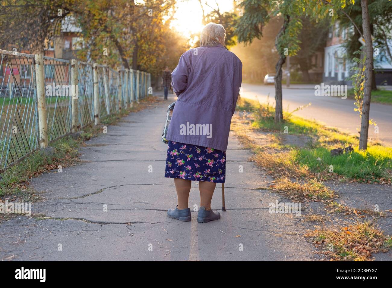 Alte Frau Großmutter mit einem Stock, lahm, etwa achtzig, auf der Straße alte Frau zu Fuß entlang der Stadtpromenade Stockfoto