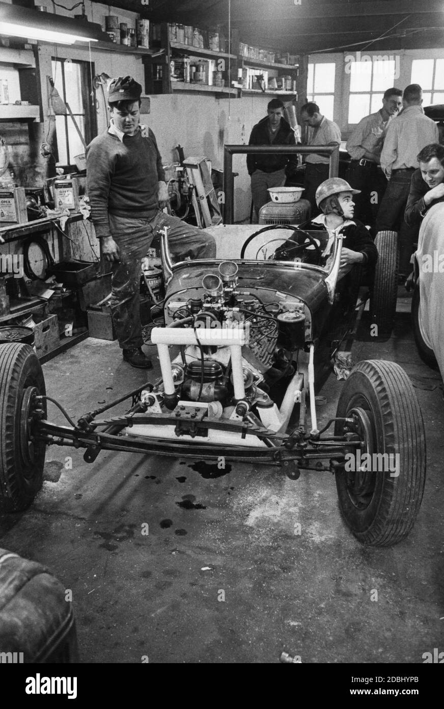 Jugendliche Jungen treffen sich in einer Garage, um an einem hausgemachten Hot Rod zu arbeiten, der aus dem Chassis eines alten Ford Model T und Teilen eines Cadillac, eines Lincoln und zweier weiterer Ford-Automobile, New York, 1955, gebaut wurde. (Foto: United States Information Agency/RBM Vintage Images) Stockfoto