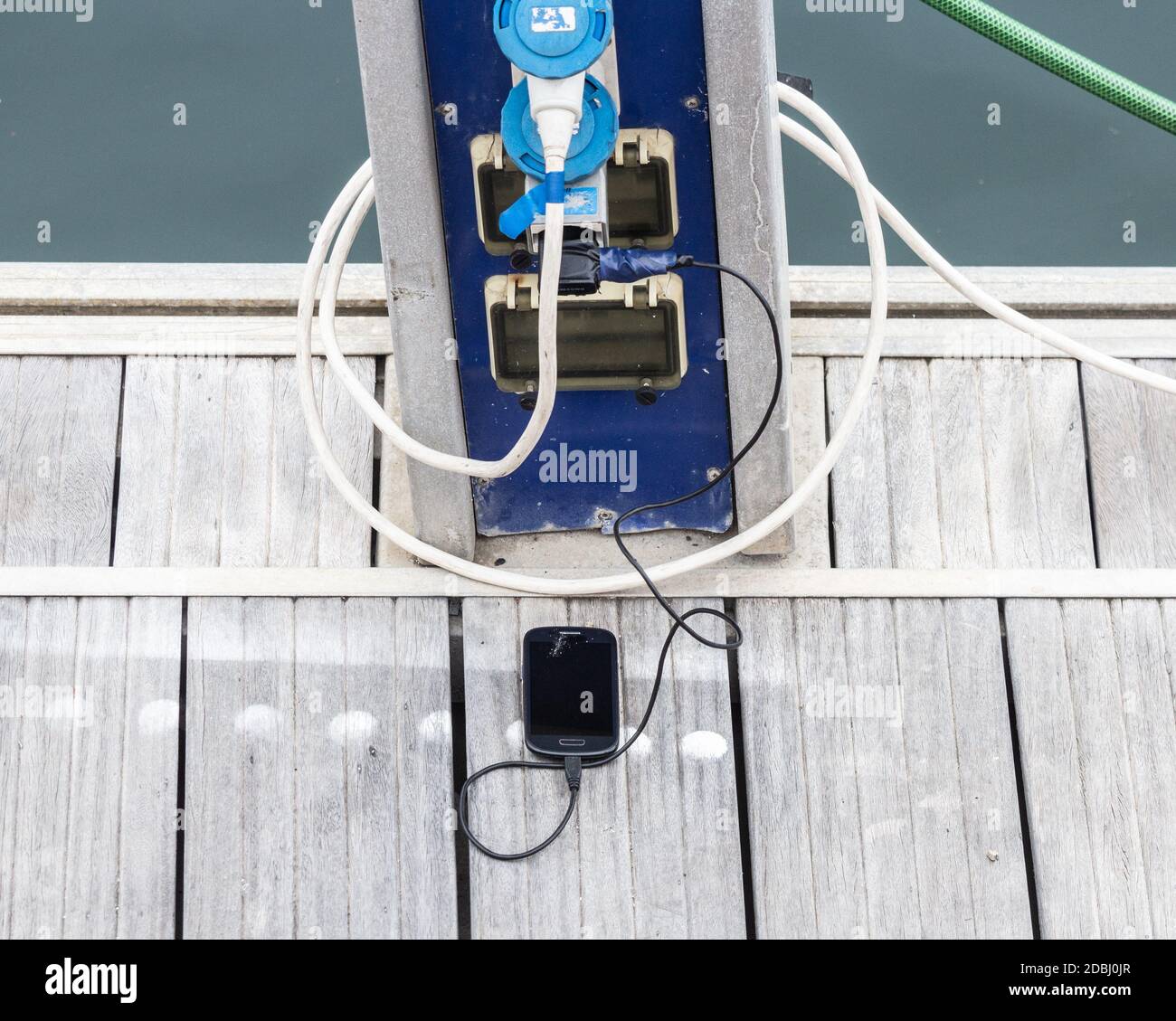 Handy/Handy aufladen neben der Yacht am Yachthafen. Stockfoto