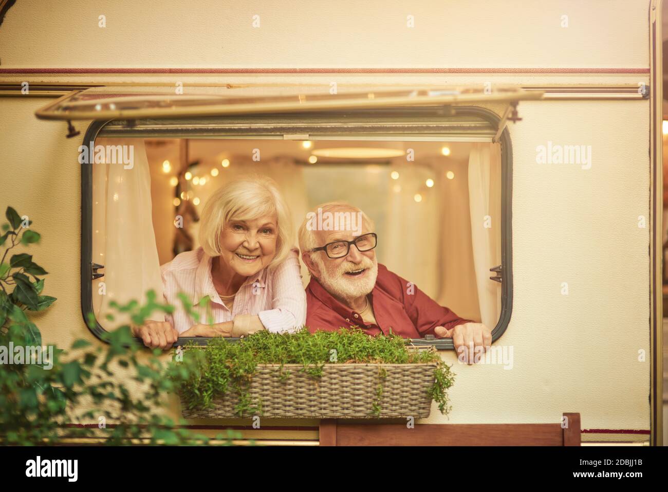 Glückliches älteres Paar, das sich in ihrem Wohnmobil ausruhte, während es aus dem Fenster schaute. Reise- und Lifestyle-Konzept Stockfoto