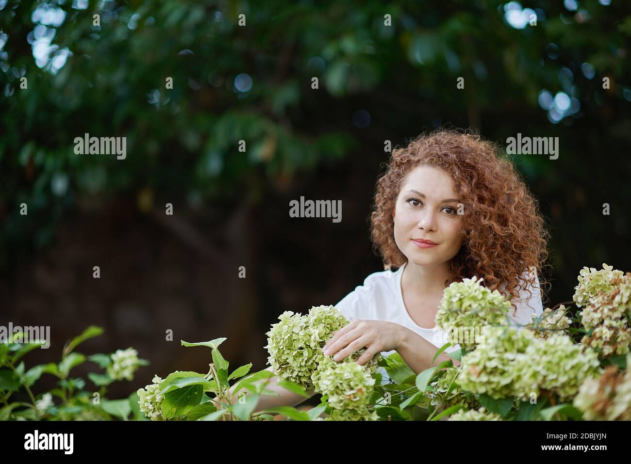 Porträt einer glücklichen jungen Frau draußen in einem Garten Stockfoto