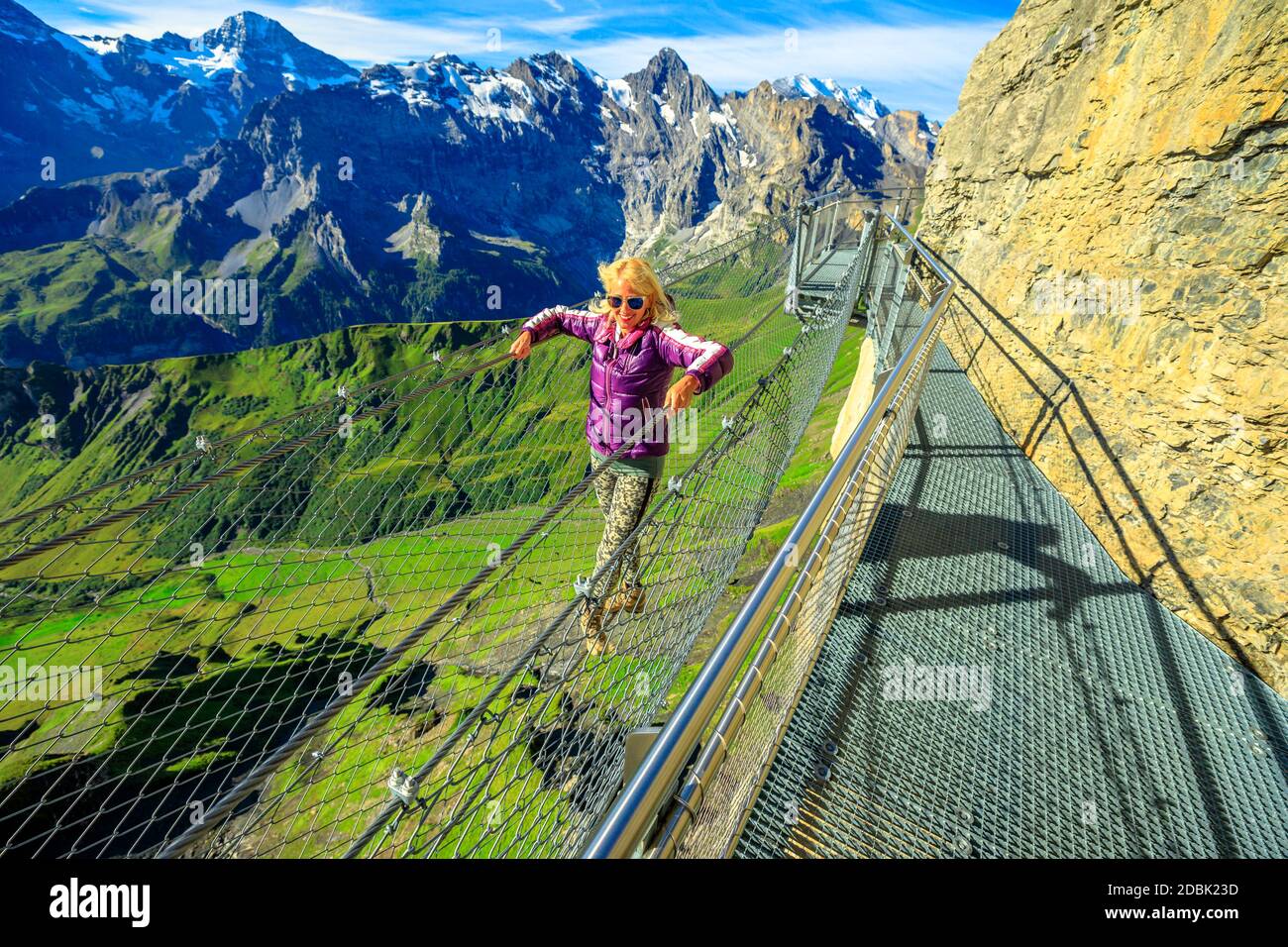 Thrill Walk auf Schilthorn, Berner Voralpen, Kanton Bern in der Schweiz. Kaukasische Frau geht auf einem Netz zwischen hohen Felswänden in der Mitte Stockfoto