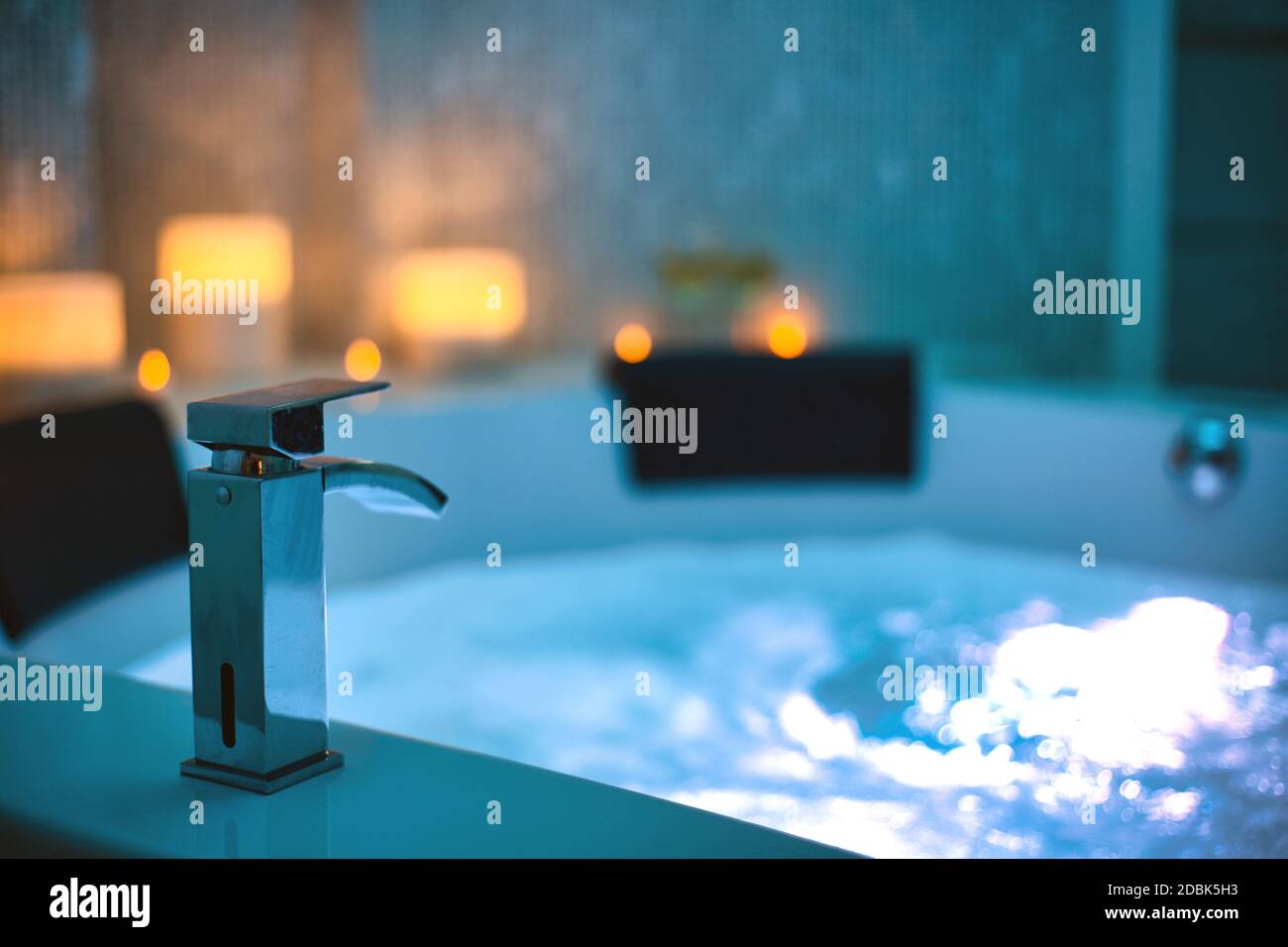 Blaues sprudelndes Wasser im Spa Jacuzzi Close-up Wasserhahn mit Kerzen auf dem Hintergrund, entspannen und Lifestyle Abstrakten Hintergrund mit blauen Lichtern dekoriert Stockfoto