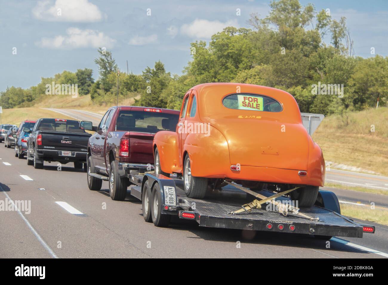 Aug 13 2019 Ft Worth USA Linie von Autos und LKW auf Autobahn - hinten zieht man Anhänger mit orange Oldtimer geschnallt auf mit für Verkauf Zeichen in zurück wi Stockfoto