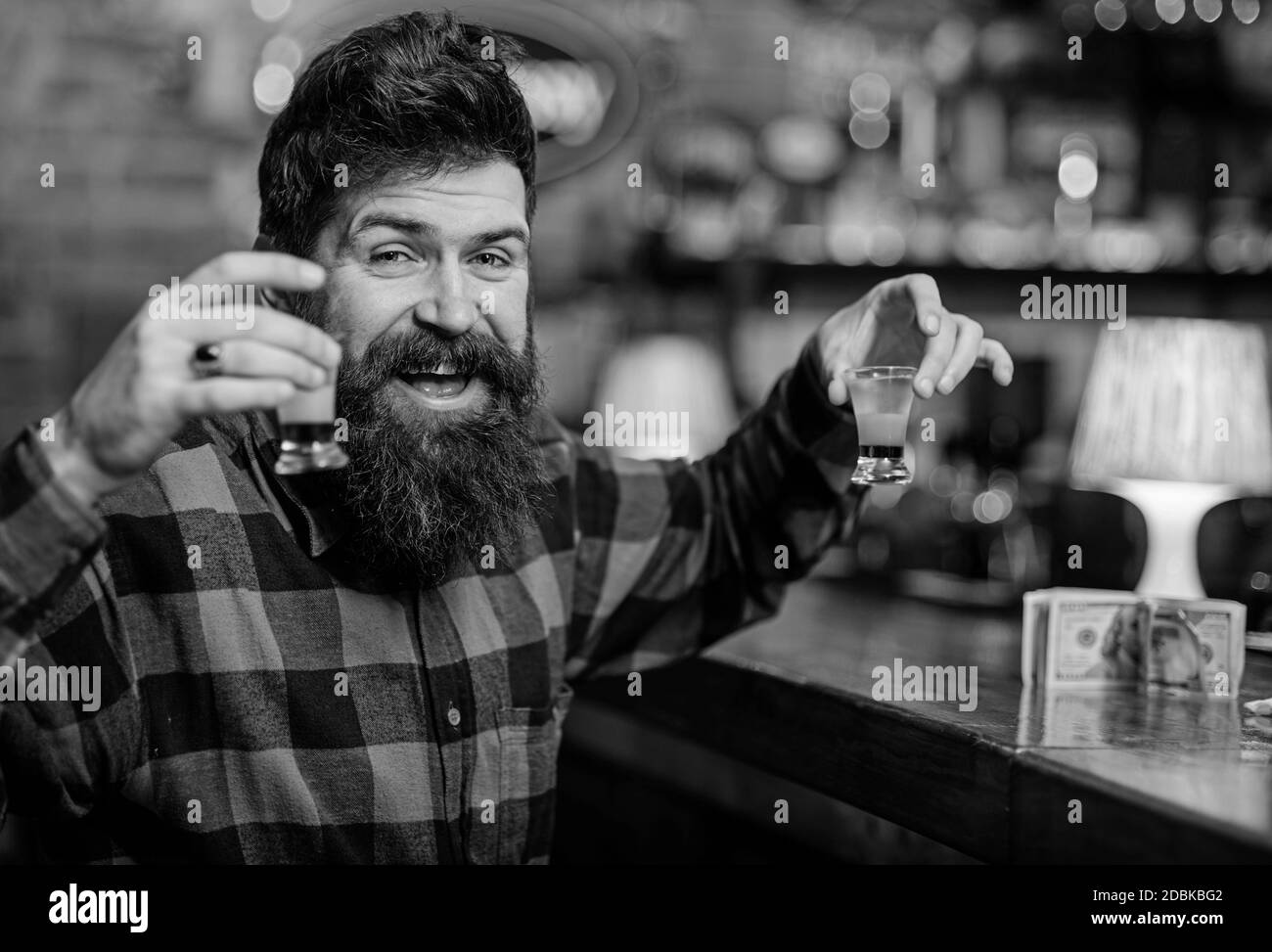 Cocktails und Alkohol Konzept. Kerl verbringen Freizeit in der Bar, defokussed Hintergrund. Hipster hält Glas mit alkoholischen Getränken, bunte kurze Cocktails. Mann mit fröhlichem Gesicht sitzt allein an der Theke. Stockfoto