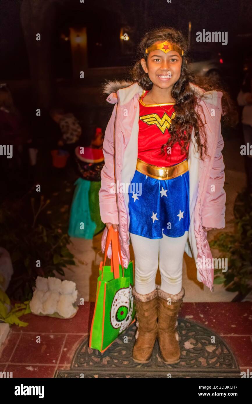 10-31-2017 schönes kleines Mädchen in Wonder Woman Kostüm und gekleidet Ein rosa Mantel wartet an Halloween auf Süßigkeiten Stockfoto