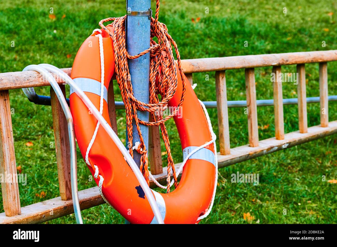 Leiter und orangefarbene Rettungsboje am Rande eines Sees in einem Park. Stockfoto