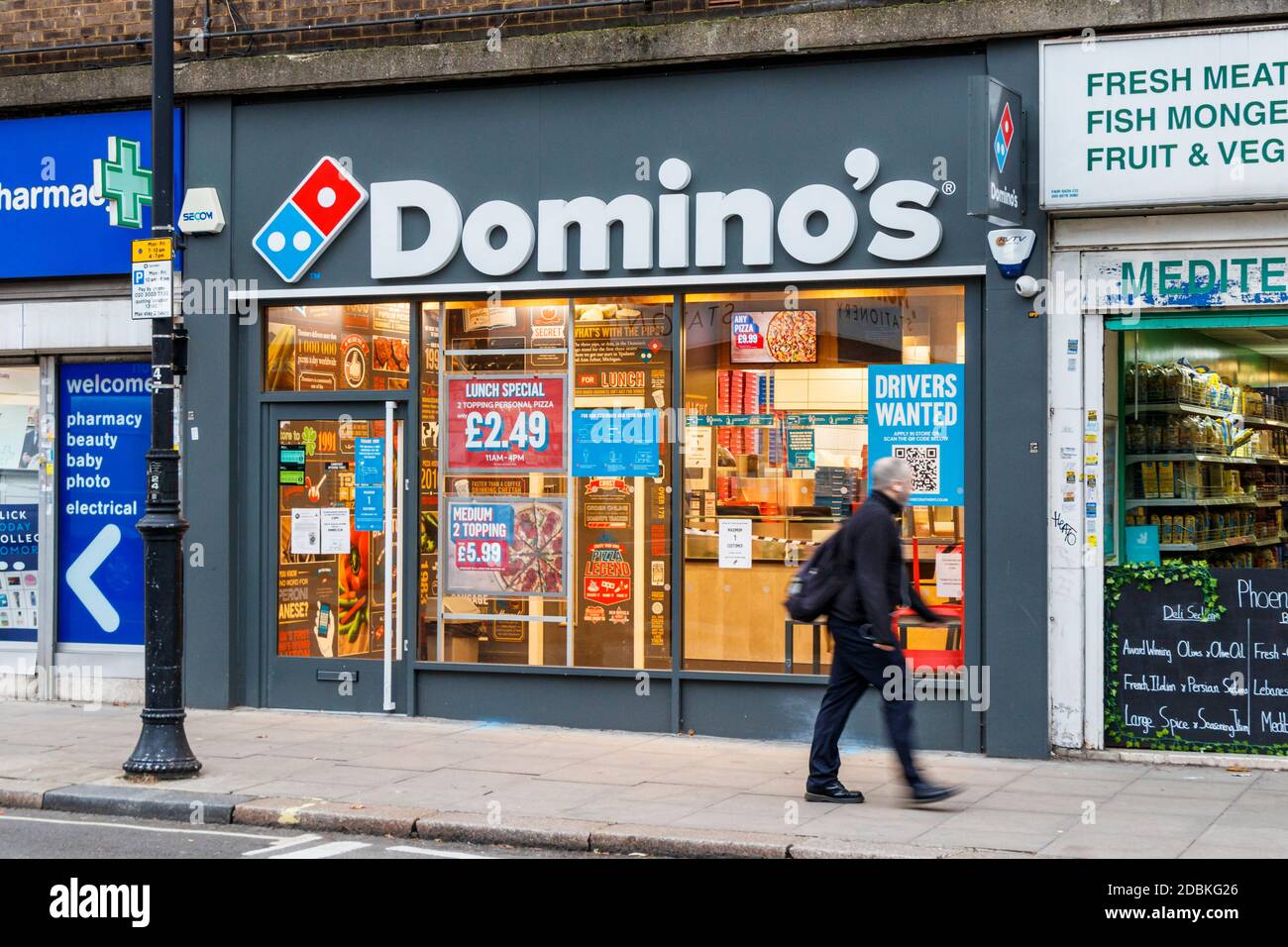 Ein Mann geht an Domino's Pizza vorbei, die während des zweiten Coronavirus-Pandemiesperrens zum Mitnehmen geöffnet ist, Kentish Town, London, Großbritannien Stockfoto