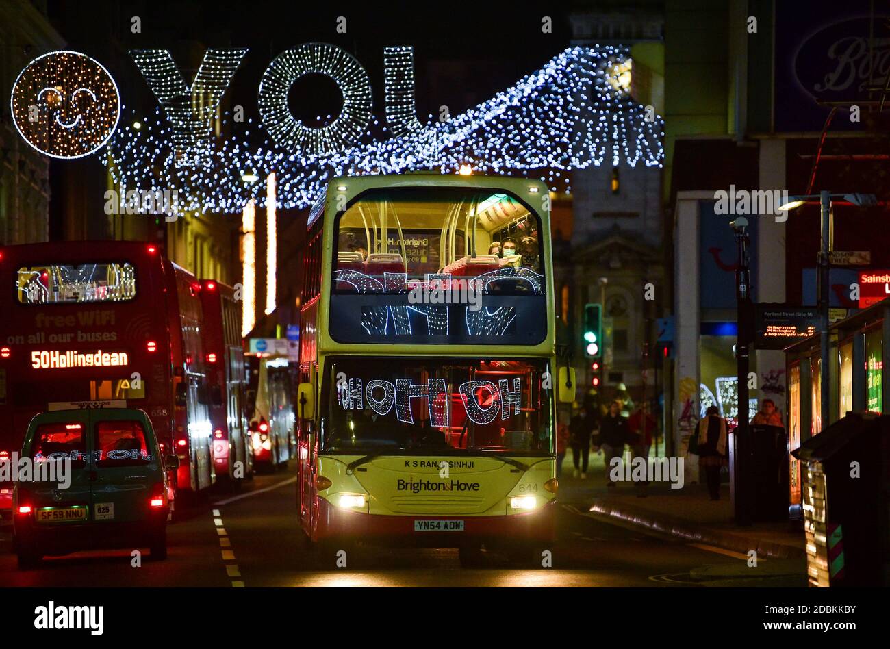 Brighton Sussex UK 17. November 2020 - Busse mit festlichen Botschaften, die sich in den Fenstern spiegeln, passieren unter den Weihnachtslichtern in North Street , Brighton und verleihen dem Coronavirus COVID-19 Sperrbeschränkungen in England etwas Glanz : Credit Simon Dack / Alamy Live News Stockfoto