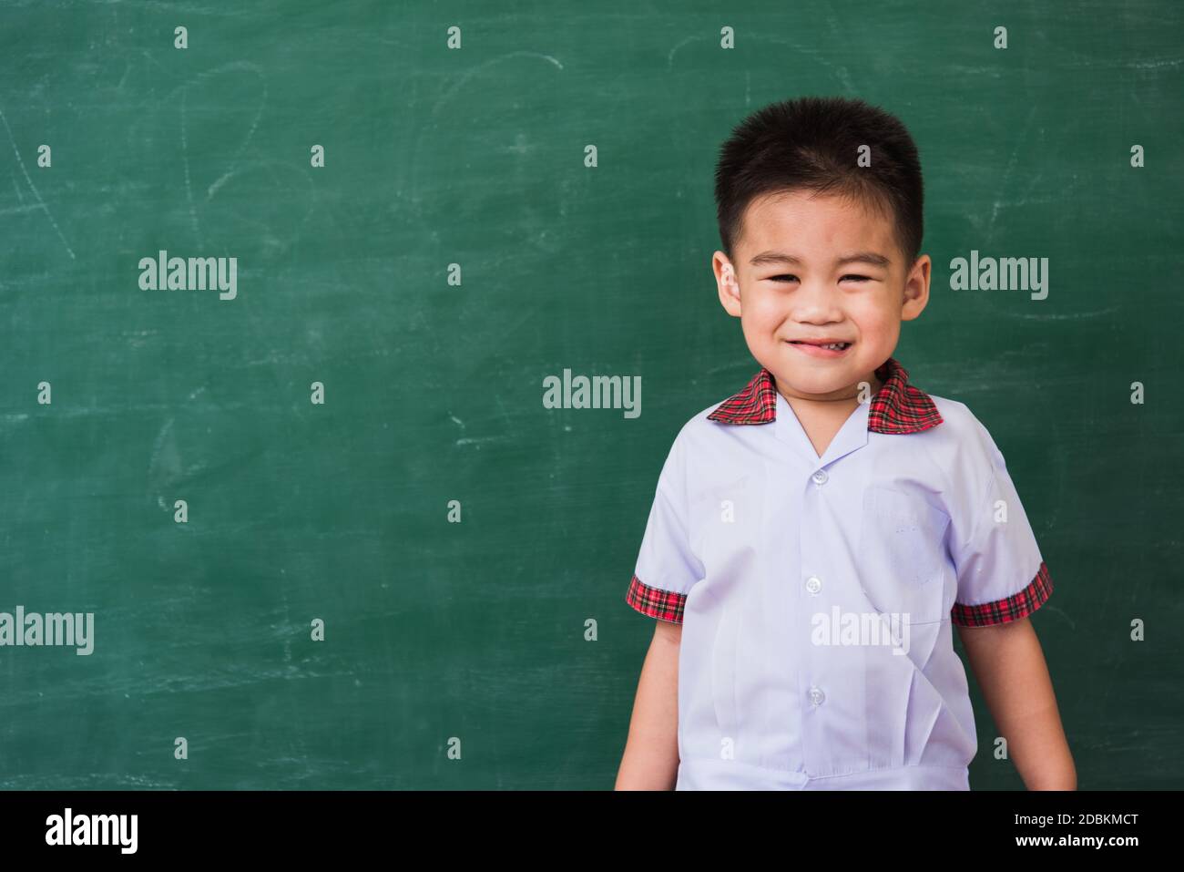 Zurück zur Schule. Glücklich asiatisch lustig niedlich kleinen Kind junge aus dem Kindergarten in Schüler Uniform lächelnd auf grüne Schule Tafel, zum ersten Mal zur Schule Stockfoto