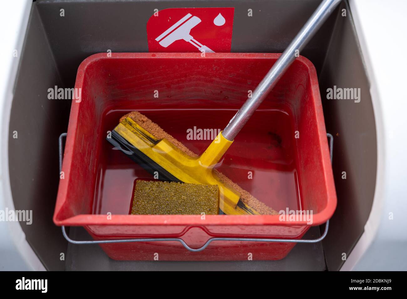 Reinigungsset mit Rakel, Schwamm und Wasser für Windschutzscheiben in einem roten Eimer an einer Tankstelle, ausgewählter Fokus, enge Schärfentiefe Stockfoto
