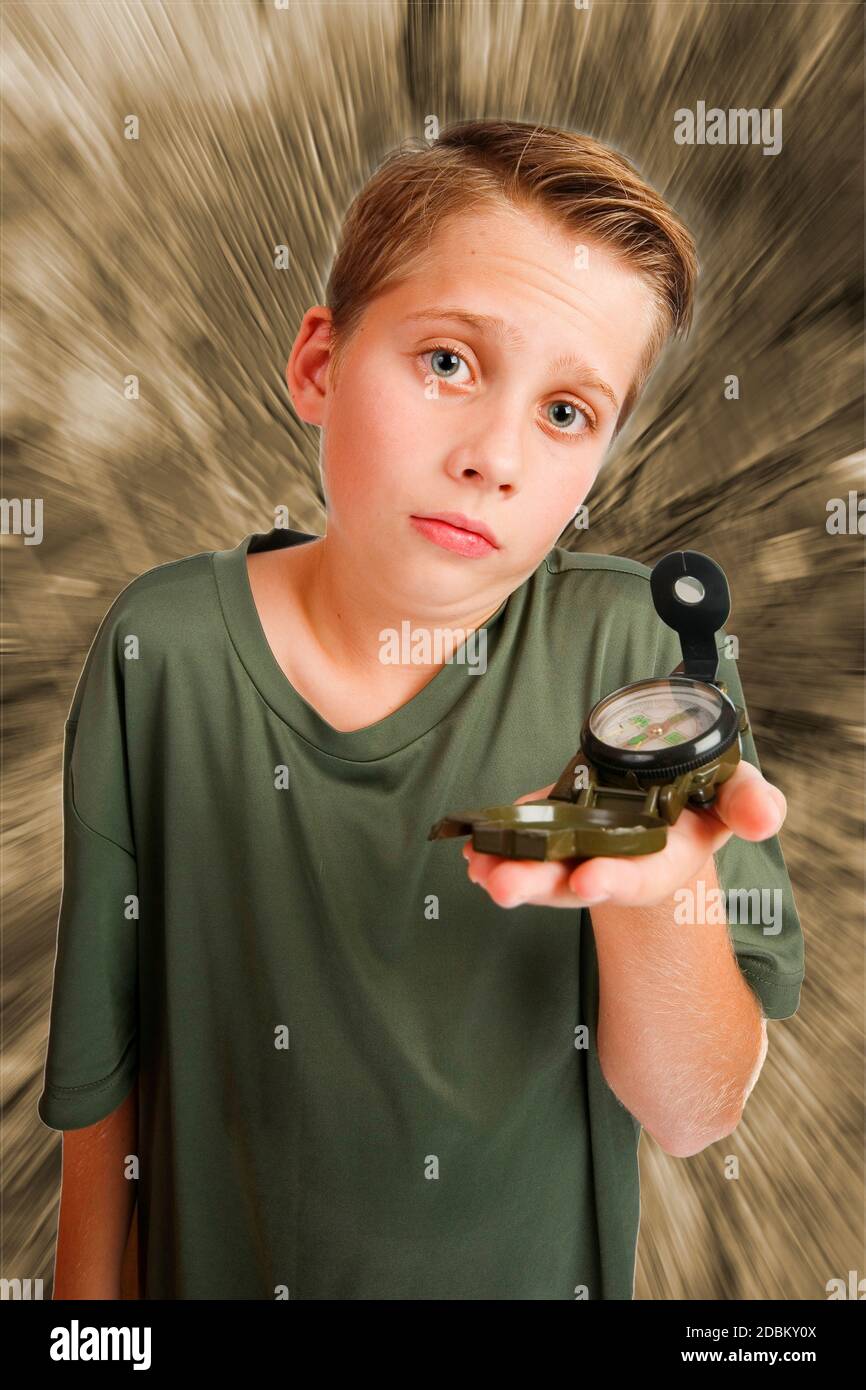 Bild eines 12-jährigen kaukasischen Jungen in einer erhöhten, Weitwinkel-Dreiviertel-Ansicht mit einem Kompass auf der linken Hand, Blick auf die Kamera hilflos ein Stockfoto