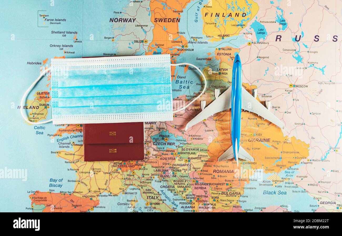 Spielzeug eines Flugzeugs, medizinische Maske und Reisepass auf der Europakarte. Stockfoto