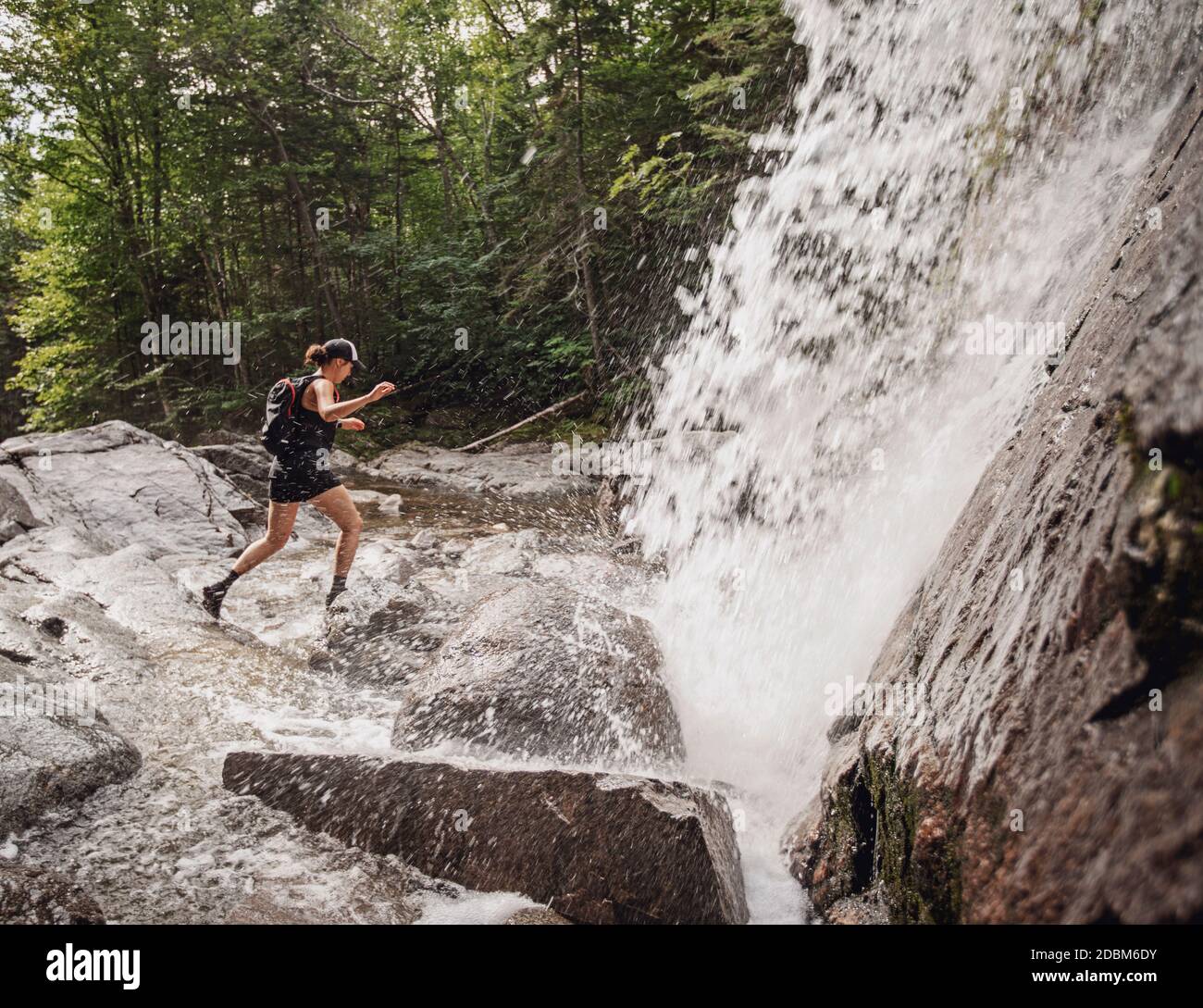 Wanderer springen über Felsen vor dem Wasserfall, New Hampshire, USA Stockfoto