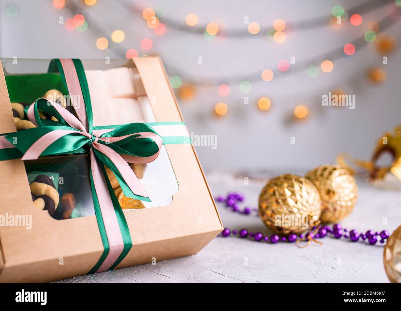 Box mit Satinbändern und leckeren Leckereien für Neujahr und Weihnachten. Neujahrsdesserts auf hellem Hintergrund. Frohe weihnachten Stockfoto