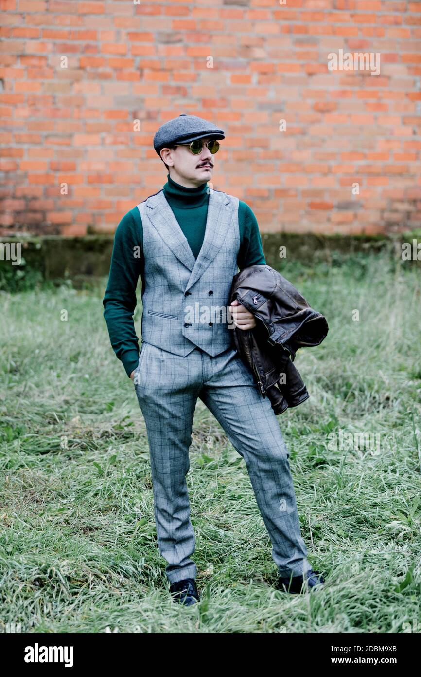 Gut gekleideter Mann mit grauem Retro-Anzug, Mütze und grünem Jersey  Stockfotografie - Alamy