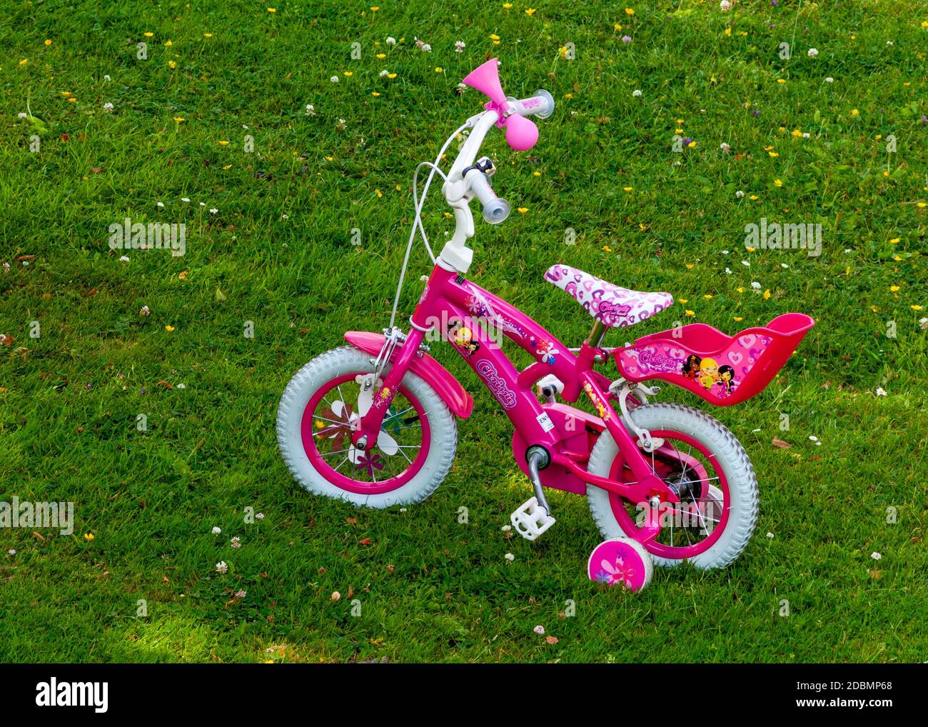 12 Zoll rosa Mädchen Pedal Bike mit Training Räder in Offener Schatten auf grünen Wiese Hinterhof Stockfoto