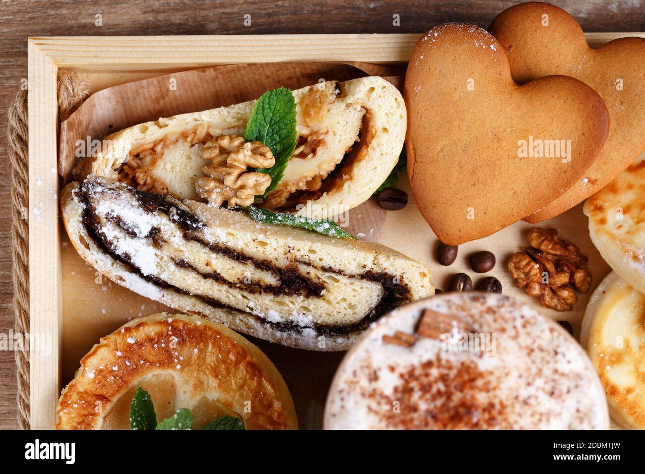 Apfel- und Mohn-Strudel, Kekse und duftender Zimtkaffee auf einem rustikalen Holztablett. Draufsicht, Nahaufnahme. Selektiver Fokus. Stockfoto