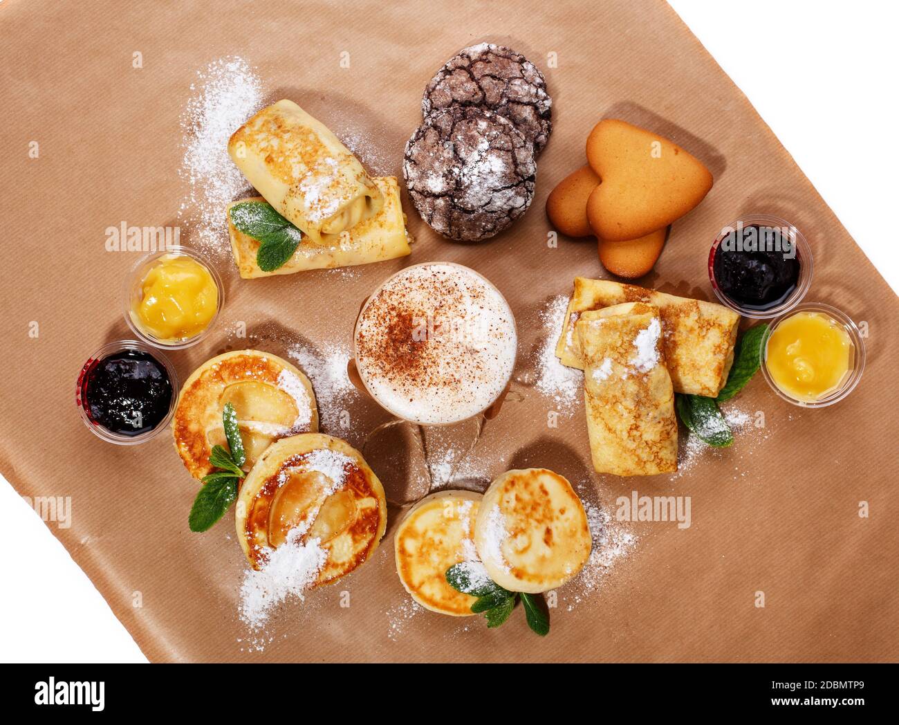 Zimtkaffee, verschiedene Marmeladen und hausgemachte Kekse, Strudel und Käse. Handgemachte Desserts und Kaffee in Papiertasse auf braunem Hintergrund. Oben Stockfoto