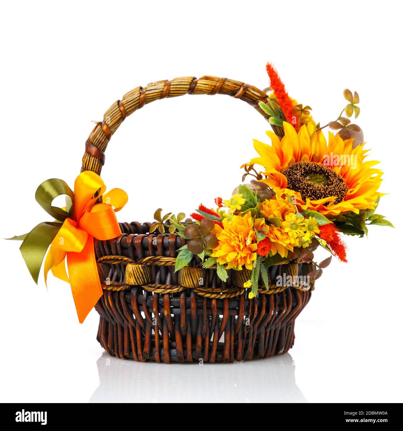Originaler dunkelbrauner Korbkorb mit Blumenarrangements. Tolle Landschaft mit gelben Blumen, Grün und einer großen Sonnenblumenblume. Warenkorb in Stockfoto