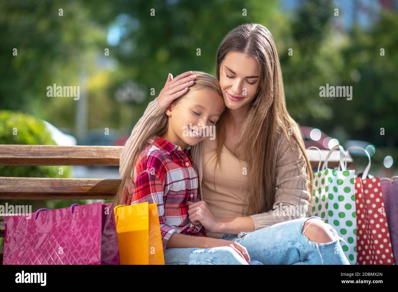 Glücklich Mutter umarmt ihre Tochter auf Bank im Park Stockfoto