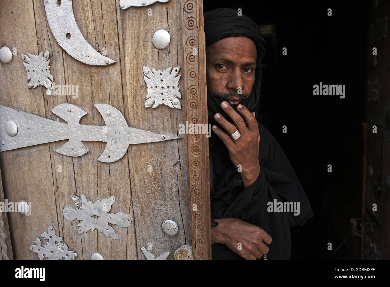 Mann, der in der Sidi Yahia Moschee neben einer alten Holztür in Timbuktu, Mali, Westafrika, abgebildet ist Stockfoto