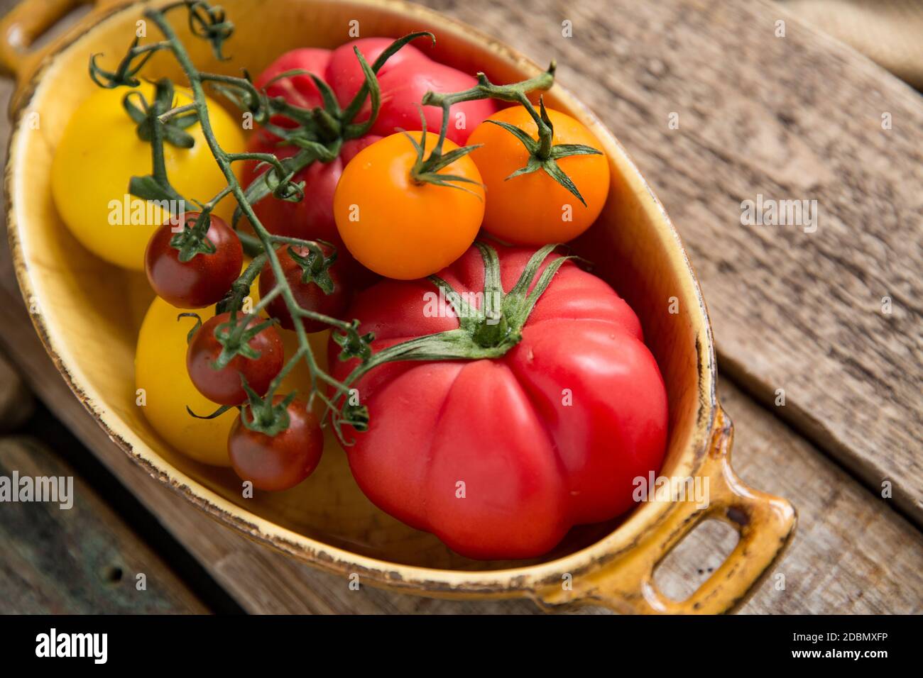 Eine Auswahl von ganzen Erbstück Tomaten auf einem hölzernen Hintergrund angezeigt. England GB Stockfoto