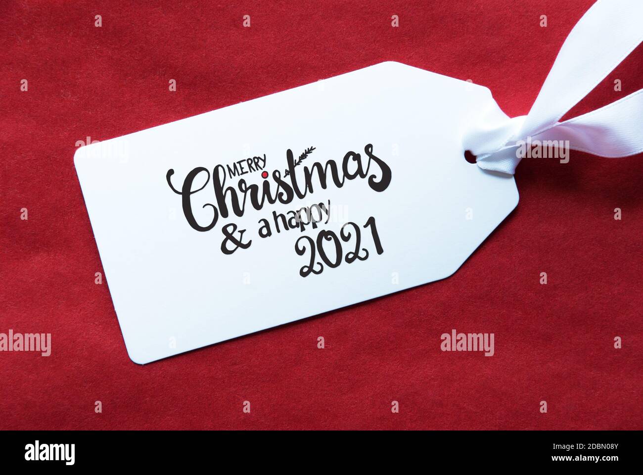 Label mit englischer Kalligraphie Frohe Weihnachten und EIN Happy 2021. Roter Strukturierter Hintergrund Stockfoto