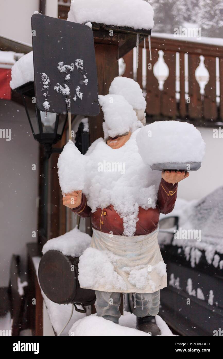 Holzstatue bedeckt mit frischem Schnee vor einem Restaurant, Gröden, Dolomiten, Italien Stockfoto