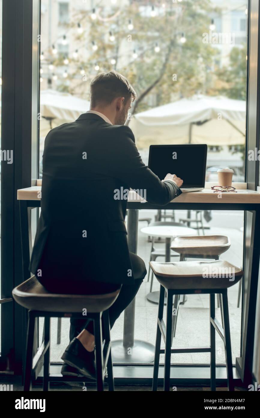 Junger Geschäftsmann sitzt in einem Café und arbeitet an der Notebook Stockfoto