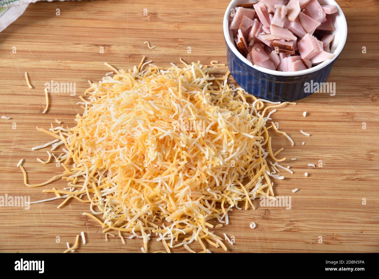 Eine Mischung aus vier Käsesorten auf einem Schneidebrett zerkleinert Mit einem Gericht gewürfelten Schinken Stockfoto