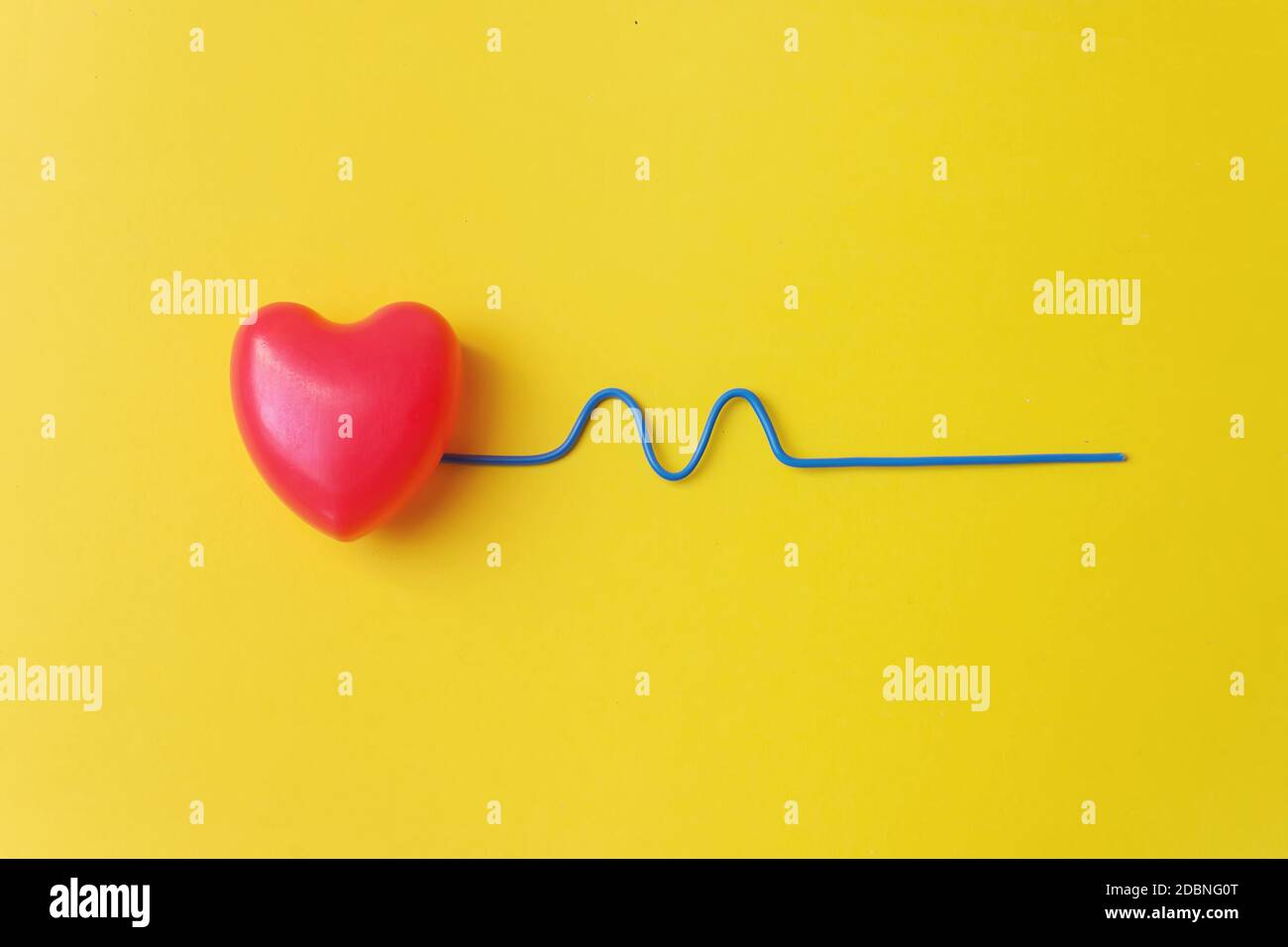 Rotes Herz mit einem blauen gebogenen Draht, der einen Herzschlag darstellt. Gesundes Konzept. Vitalenergie-Konzept Stockfoto