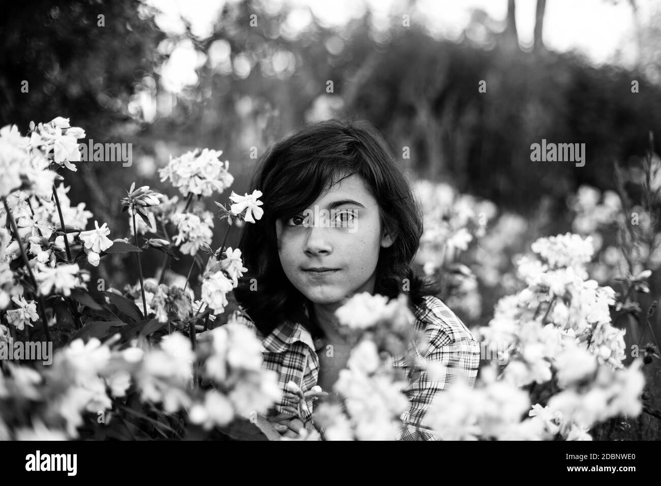 Schwarz behaart teen Mädchen im Garten unter Blumen. Schwarzweiß-Foto. Stockfoto