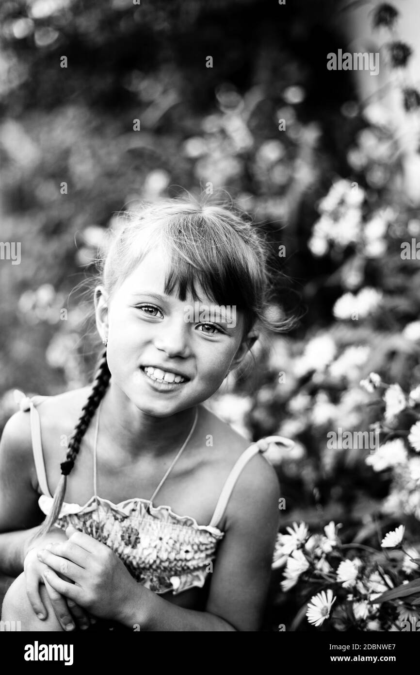 Kleines Mädchen im Garten zwischen Blumen. Schwarzweiß-Foto. Stockfoto