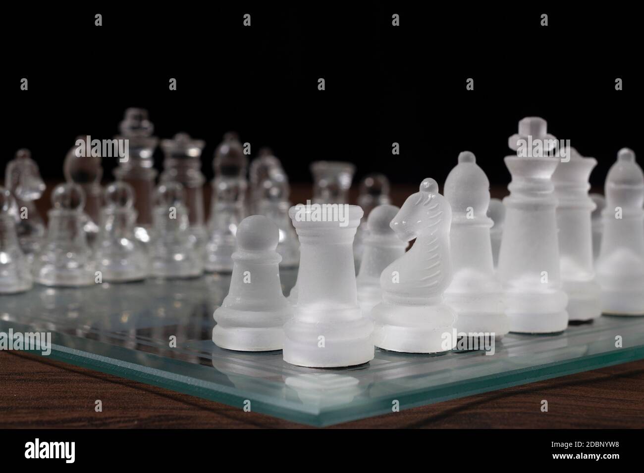 Schachspiel. Glassteine auf dem Schachbrett. Bereit, das Spiel zu starten. Stockfoto
