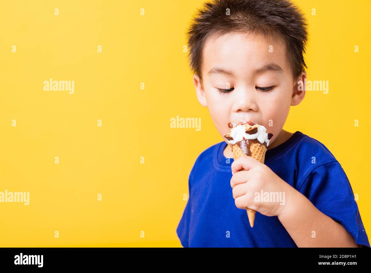 Glücklich Porträt Asian Kind oder Kind niedlich kleinen Jungen attraktiv lachen Lächeln spielen hält und essen süße Schokolade Eis Waffel-Kegel, Studio geschossen i Stockfoto