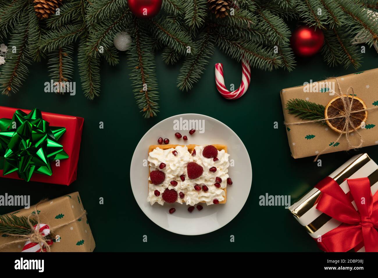 Auf einem Tisch mit weihnachtlicher Einrichtung befindet sich ein Teller mit hausgemachten Waffeln mit Schlagsahne. Stockfoto