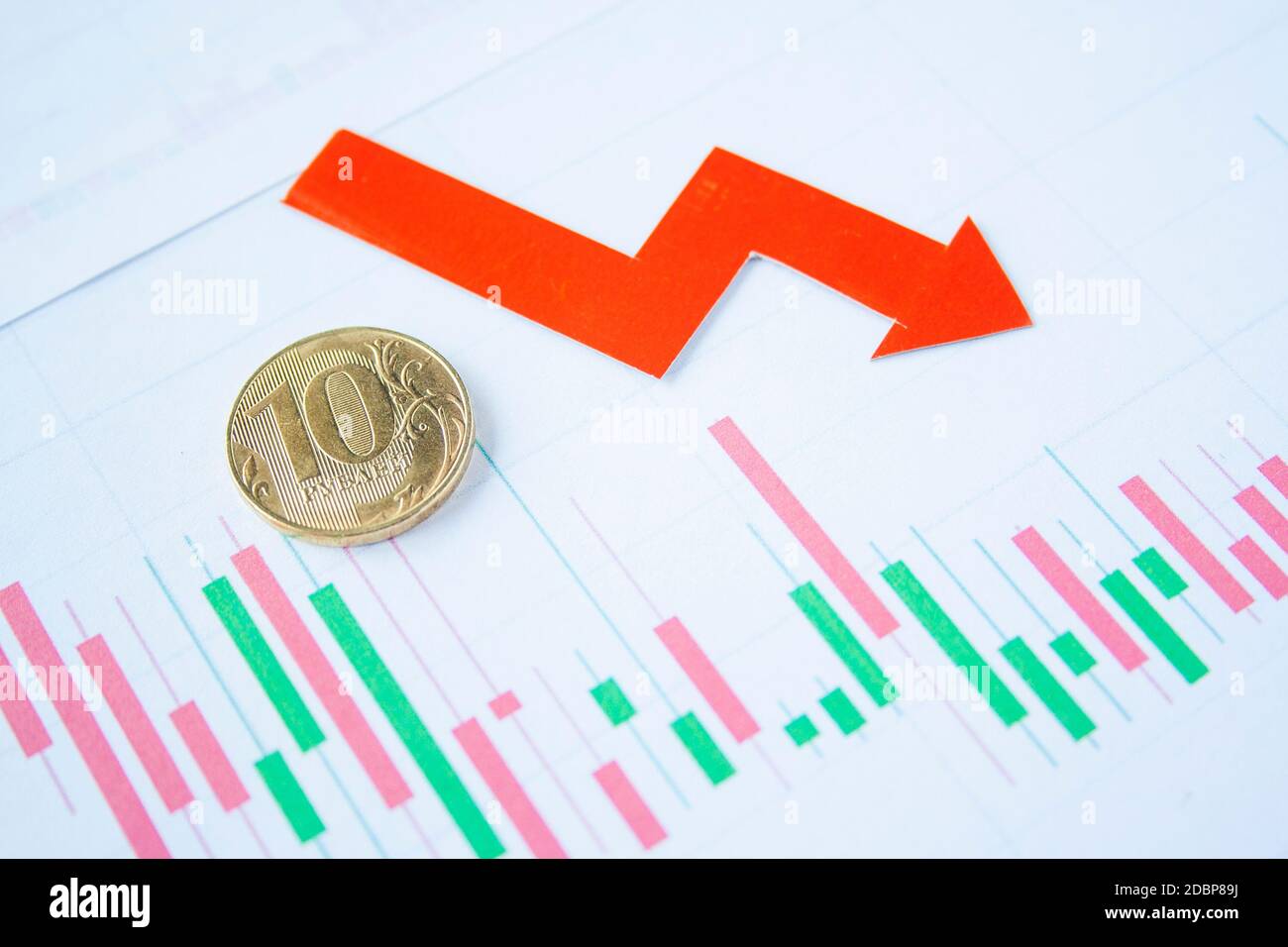 10 Rubelmünzen auf dem Währungsdiagramm mit rotem Pfeil nach unten. Wechselkurstabelle. Rubelabschreibung. Wechselkurs des Rubelfalls. Rubel zum Dollar Stockfoto