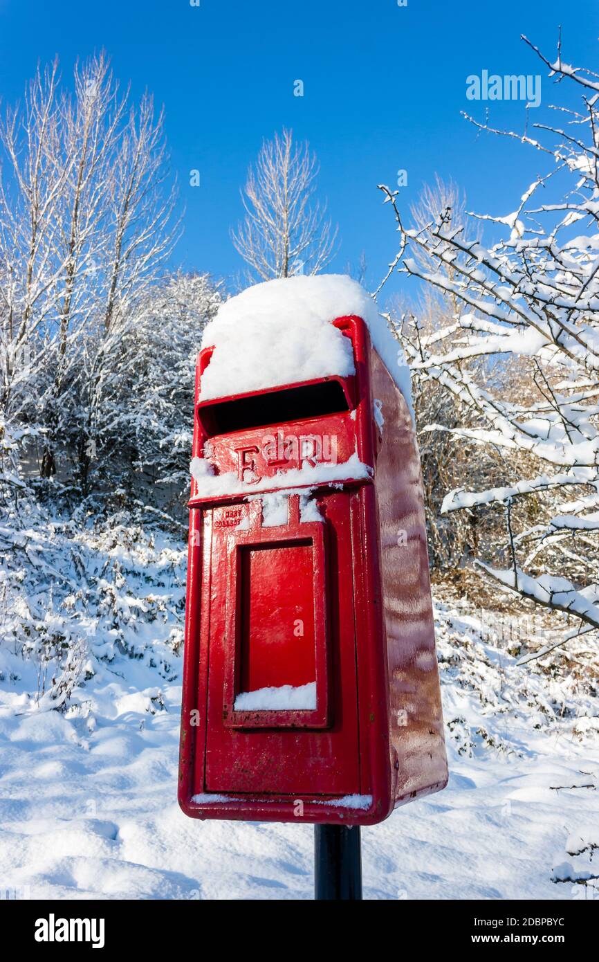 Traditionelle rote britische Briefkasten mit frischem Schneefall bedeckt Stockfoto