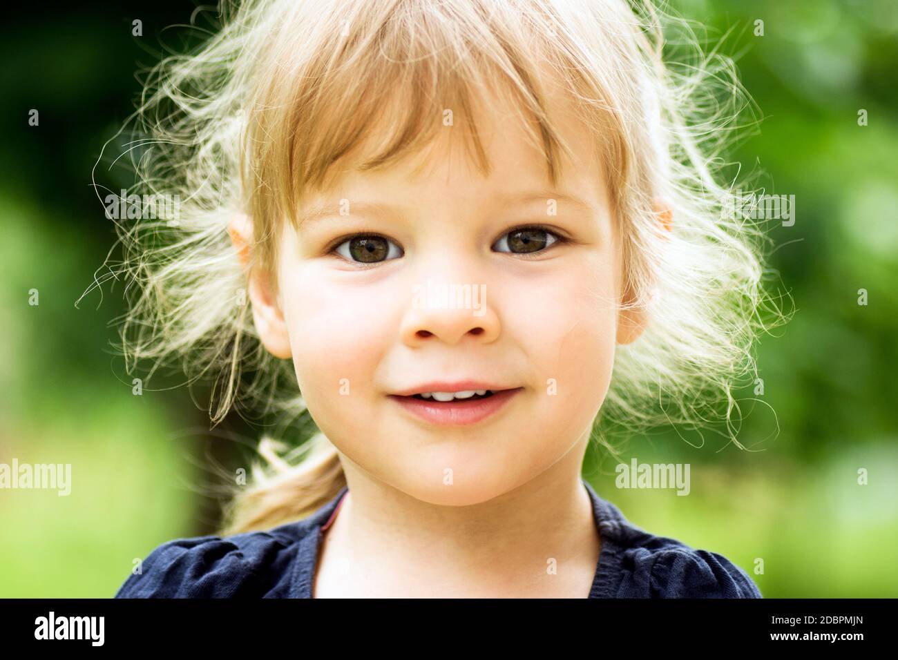 Kind Porträt von niedlichen blonden kleinen Mädchen mit zerzaust chaotisch Haar auf grünem Hintergrund. Stockfoto