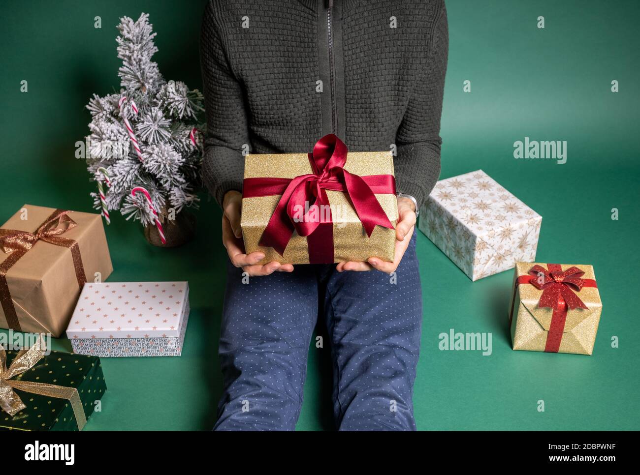 Mann mit vielen eingewickelten weihnachtsgeschenken auf grünem Hintergrund Stockfoto