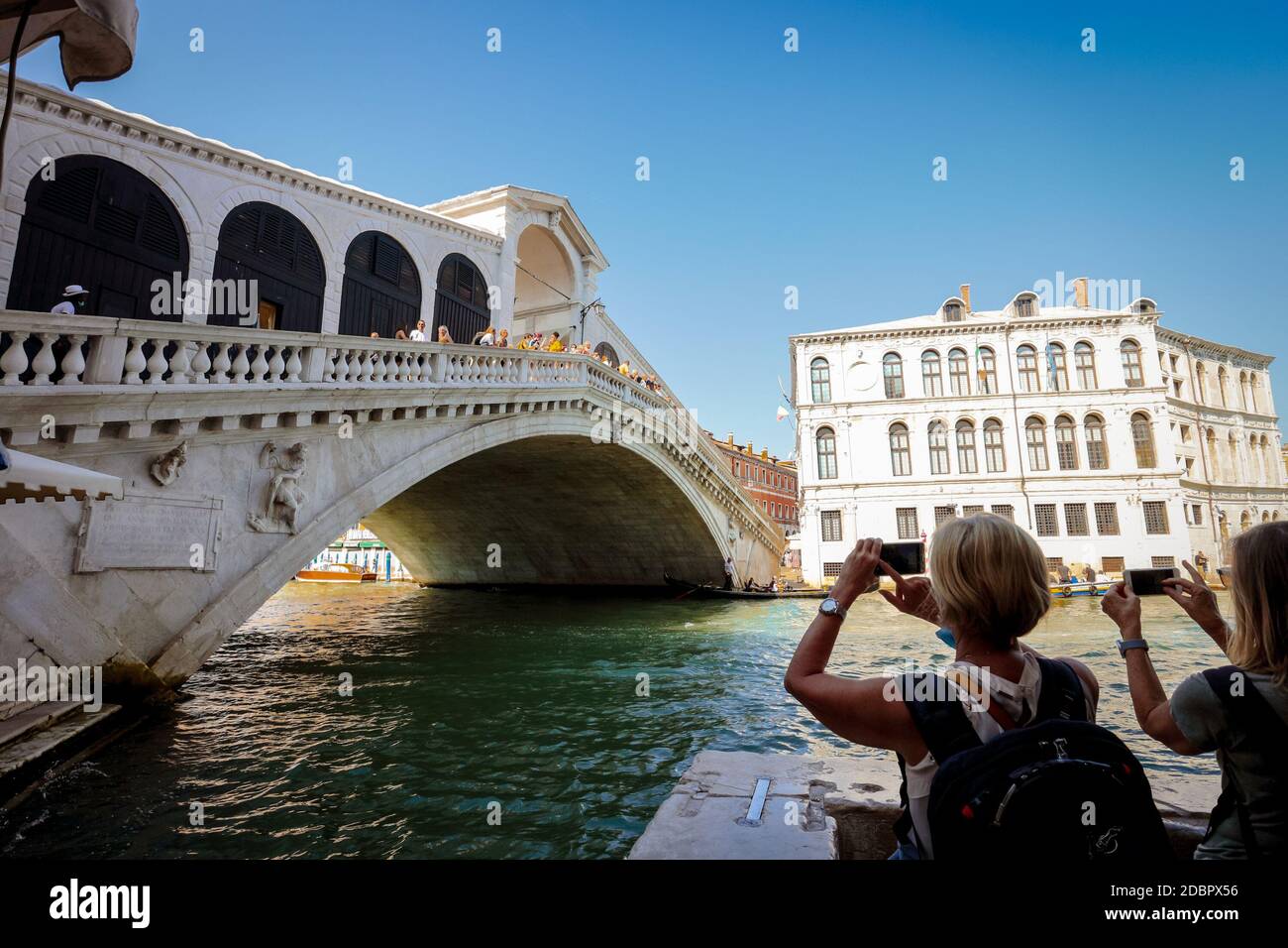 Weibliche Touristen in Venedig, Italien fotografieren die Rialtobrücke vom Canale Grande aus mit ihren Smartphones. Stockfoto