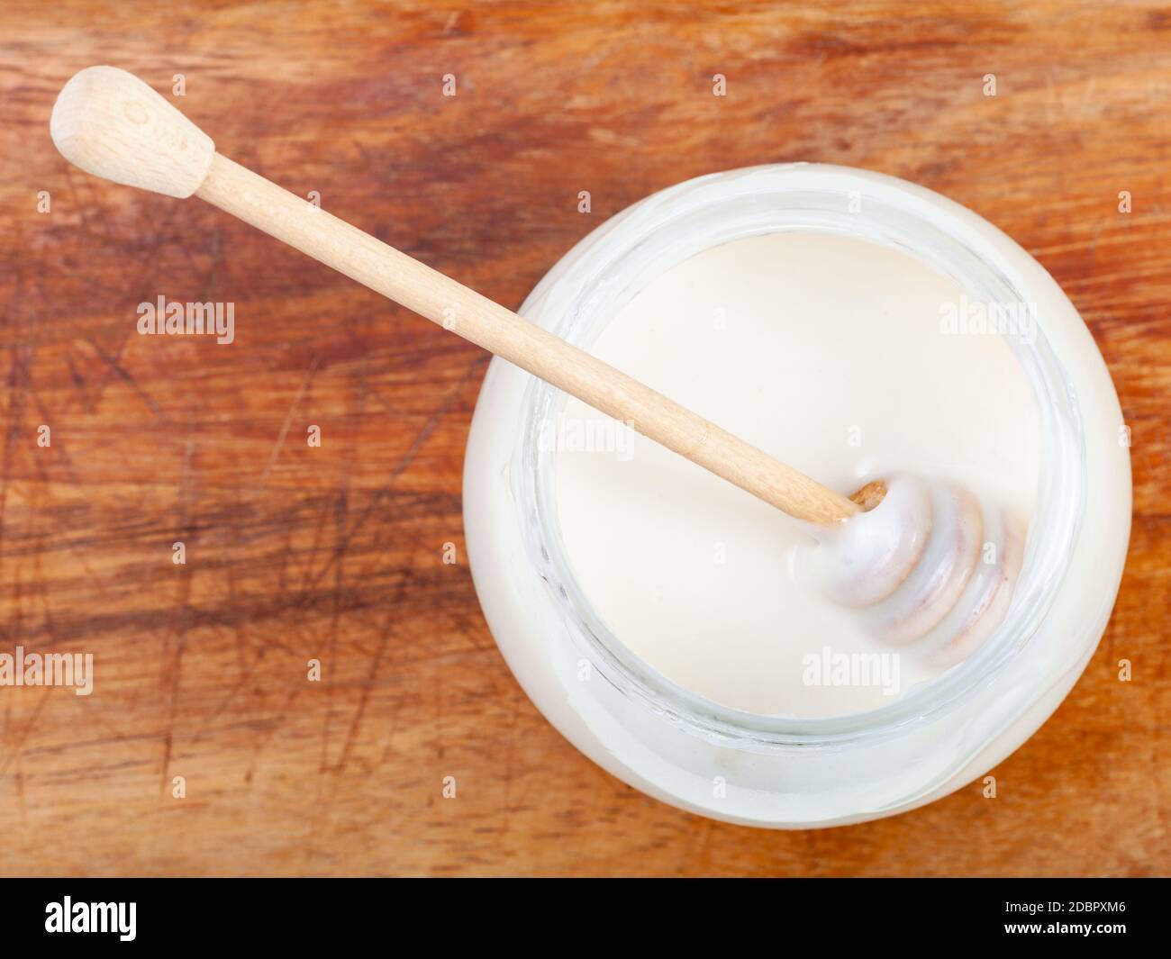 Draufsicht auf Holzstab in Glas mit natürlichen Bio-weißen Honig auf Holzbrett Stockfoto