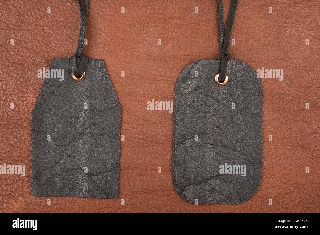 Zwei leere schwarze Leder tag Label auf braunem Leder. Ansicht von oben Stockfoto