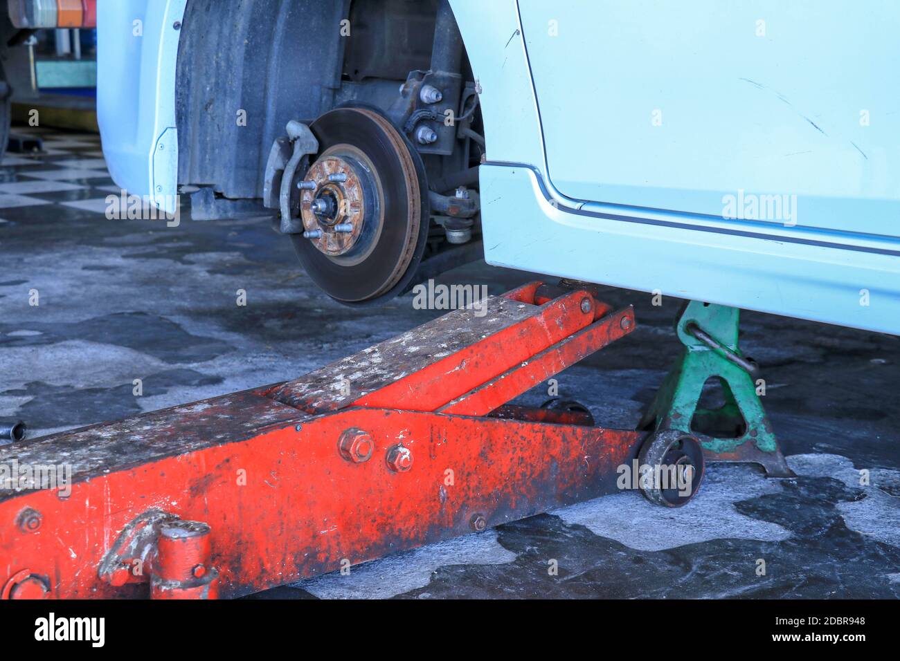 Beim Austausch der Räder eines Autos hält der Wagenheber die Karosserie in angehobener Position. Stockfoto