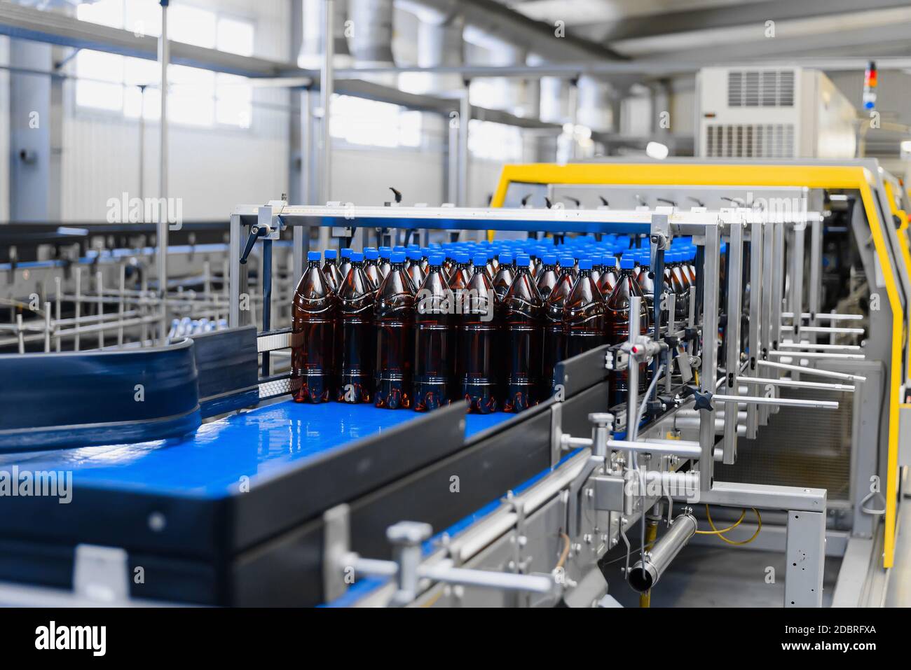 Automatische Linie für Vakuumverpackungen in einer Brauerei. Braune Kunststoffflaschen auf dem Förderband Stockfoto