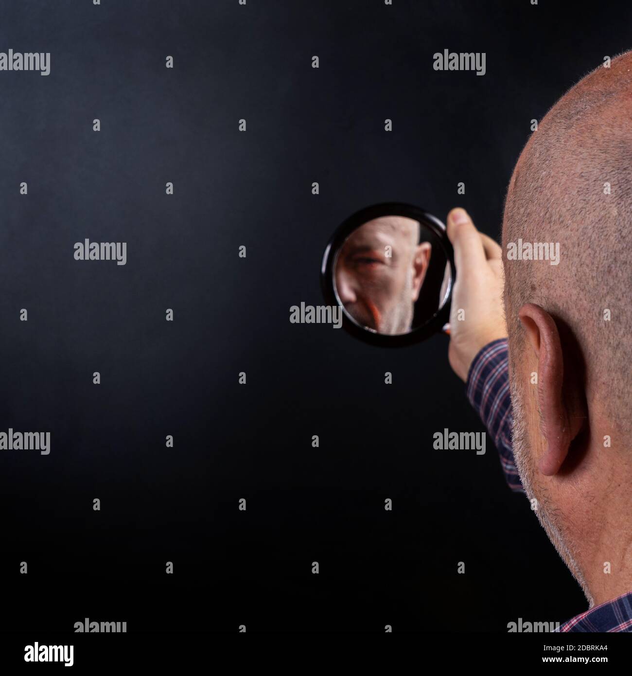 Ein Mann spiegelt sich in einem kleinen Spiegel wider Stockfoto
